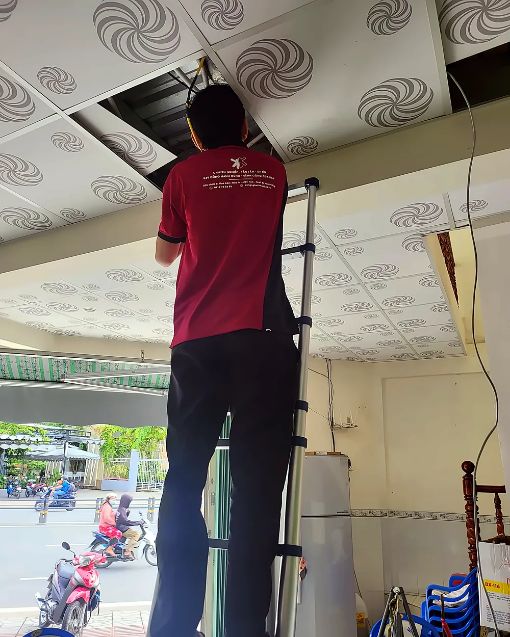 Kỹ thuật viên K39 làm việc trên thang ở trần nhà tại công trình